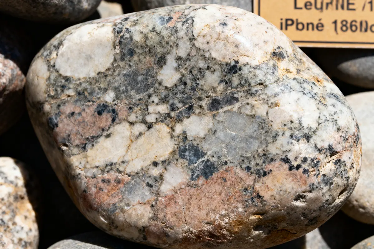 Gros plan d'un galet de granit coloré, textures variées, étiquette floue en arrière-plan.