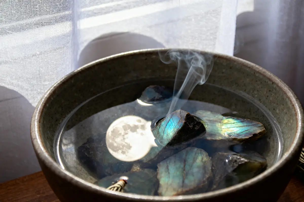Bol en céramique avec pierres irisées et reflets fumants, éclairé par lumière naturelle.