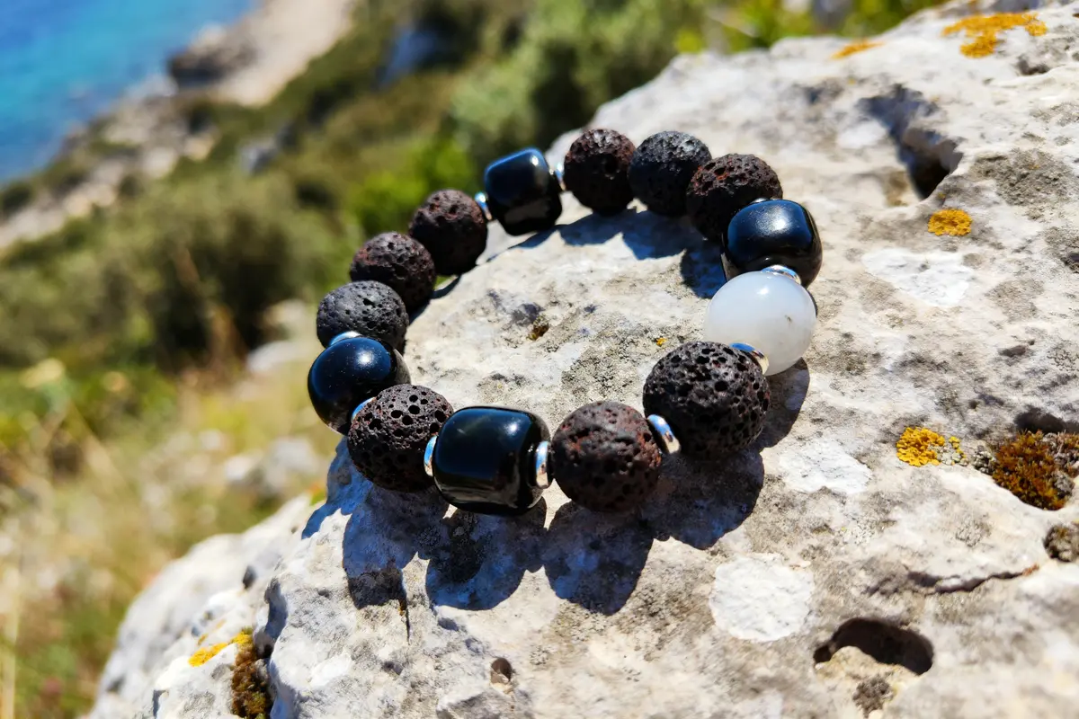 Bracelet pierre homme noir et blanc en pierres naturelles sur un rocher ensoleillé