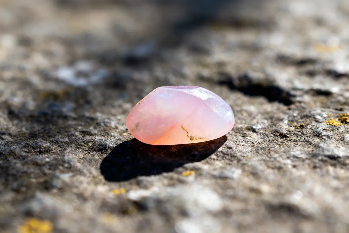 Opale rose polie posée sur une surface rocheuse en plein soleil